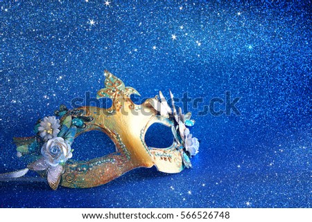 Image of gold elegant venetian mask on blue glitter background
