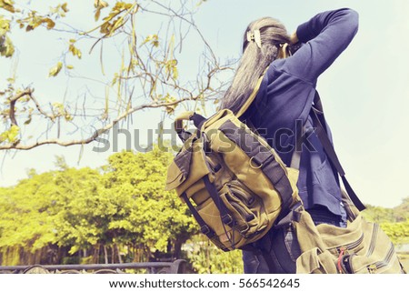 White hairs backpack photographer shooting green nature.