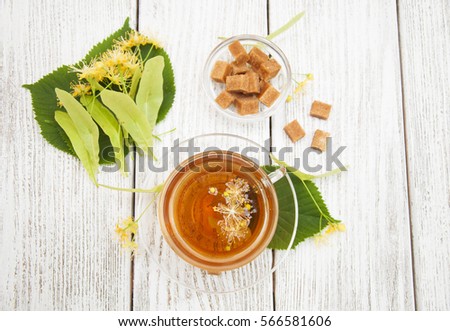 A cup of herbal linden tea with flowers on a wooden background