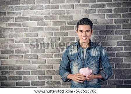 Asian young man hold a pink piggy bank