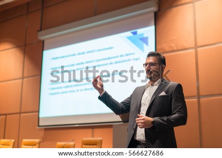 Speaker giving talk on podium at Business Conference. Entrepreneurship club. Horizontal composition. Royalty-Free Stock Photo #566627686