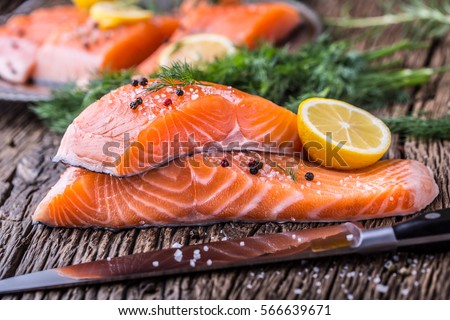 Raw salmon fillets pepper salt dill lemon and rosemary on wooden table. Royalty-Free Stock Photo #566639671