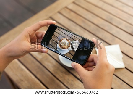 close-up hand holding phone mobile taking photo coffee on table