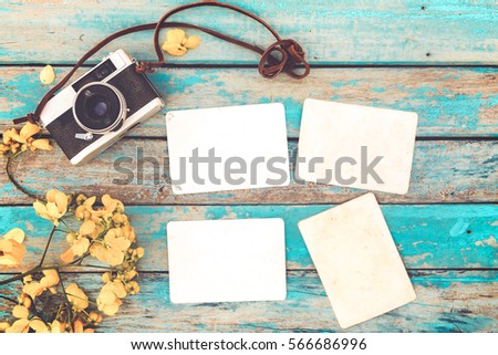 Retro camera and empty old instant paper photo album on wood table with flowers border design - concept of remembrance and nostalgia in spring. vintage style