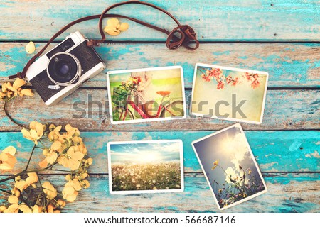 Retro camera and instant paper photo album on wood table with flowers border design - photo of remembrance and nostalgia in spring. vintage style