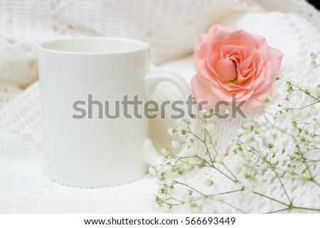 Mockup. Mug, rose, knitted fabric and details on a white table.