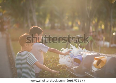 Little boy taking garbage in to the bin in the park