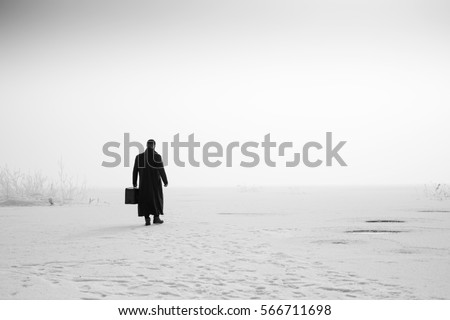 man walking with a suitcase on the frozen lake