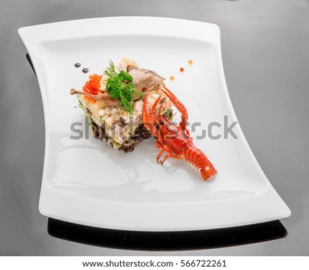 Olivier salad with trout in a white plate. Wooden background