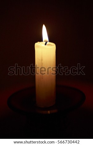 Single burning candle on a black background