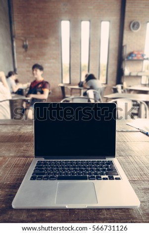 Blank screen laptop place on wooden table in coffee shop in soft focus.