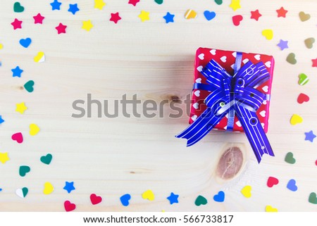 Gift box and little cardboard colored hearts on bright wooden background