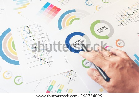 businessman hand working on wooden desk in office and there are many documents, graphs. Can be attributed to financial articles. Royalty-Free Stock Photo #566734099