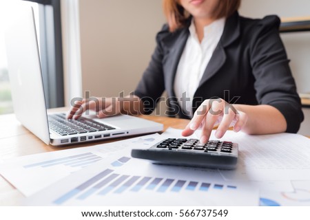 Asian female accountant or banker making calculations. Savings, finances and economy concept. Royalty-Free Stock Photo #566737549