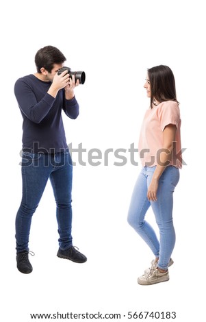 Profile view of a good looking professional photographer taking pictures of a cute model
