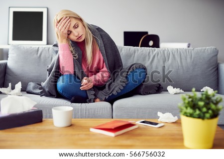 Sick woman with headache sitting under the blanket Royalty-Free Stock Photo #566756032