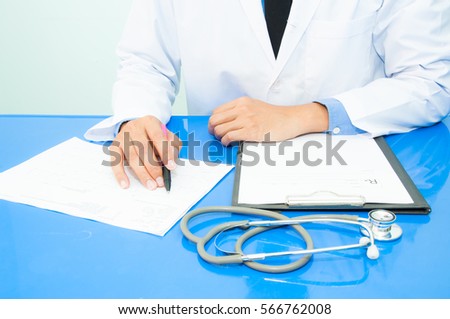Medicine doctor writing a medical prescription at his desk in the hospital.