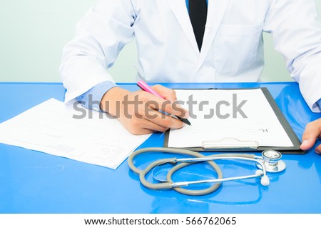 Medicine doctor writing a medical prescription at his desk in the hospital.