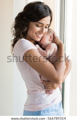 Pretty woman holding a newborn baby in her arms Royalty-Free Stock Photo #566789314