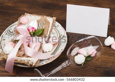 Tableware and silverware with puffy light pink roses on the wooden background