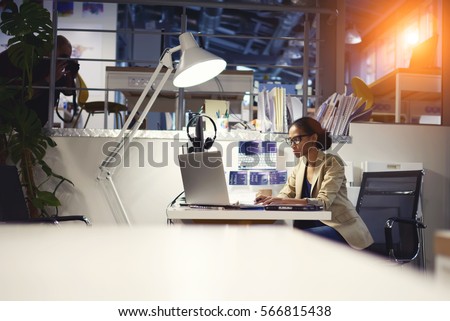 Young talented copywriter in trendy eyewear making task of executive creating advertising publication article typing text on laptop computer connected to free wireless network in office wifi zone