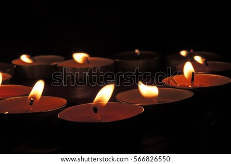 Small firing candles in catholic church on dark background. Filtered photo with effects