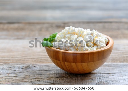 Homemade cottage cheese in a bowl on old wooden table. Royalty-Free Stock Photo #566847658