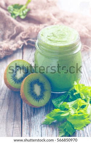 Smoothies spinach, celery and kiwi fruit in a small glass jar on old wooden table. Toned picture.