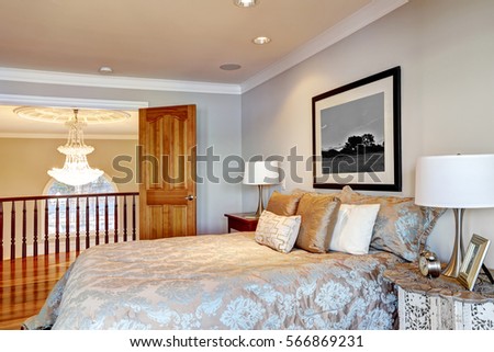 Chic master bedroom with pale grey walls paint color, queen bed dressed in blue and grey floral bedding and open doors to the landing with chandelier view. Northwest, USA