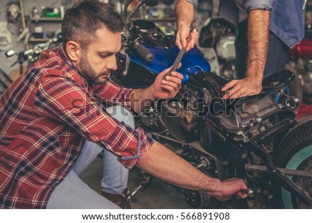 Handsome guys are repairing a motorcycle in the repair shop