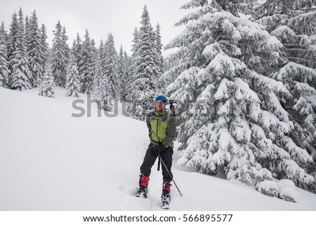 Man, traveler relaxing and enjoying life in winter mountains among snow covered pine trees after walk snowshoeing.