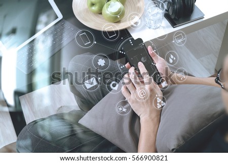 hipster hand using smart phone for mobile payments online business,headphone,sitting on sofa in living room,green apples in wooden tray,graphic interface icons virtual screen