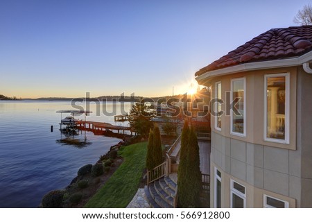 Amazing sunset view of Lake Washington and private dock from the upper balcony of luxurious Mediterranean style waterfront home. Northwest, USA Royalty-Free Stock Photo #566912800