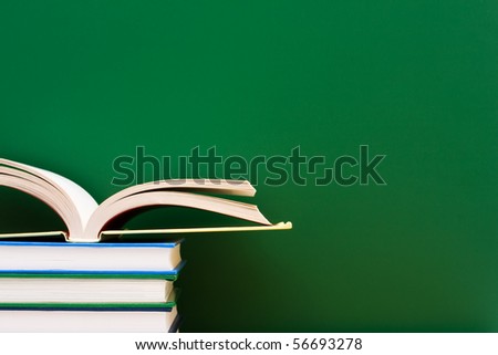Stack of  books one open in front of the chalkboard, School Days Royalty-Free Stock Photo #56693278
