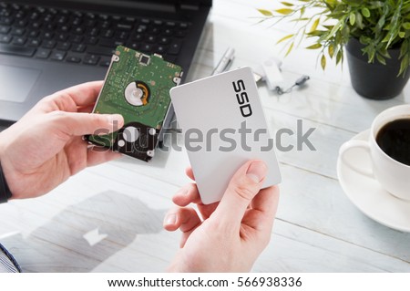 Man changes hard drive disk to a modern ssd Royalty-Free Stock Photo #566938336