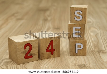 Cube shape calendar for SEPTEMBER 24 on wooden surface. 