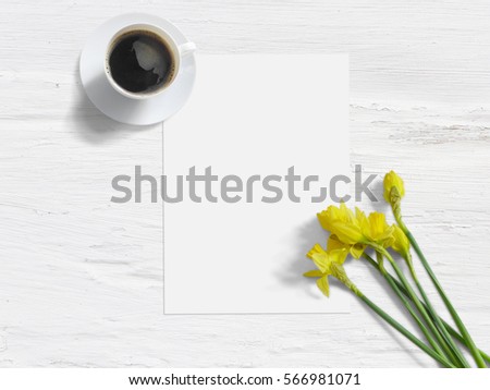 Spring styled stock photo. Feminine mock-up with daffodil flowers, Narcissus, a blank list of paper, and a cup of coffee. Shabby white background. Flat lay picture, top view. Image for the blog.