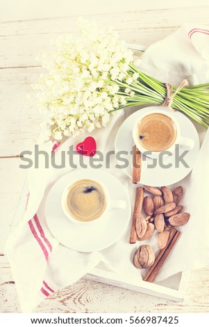 Two cups of coffee - espresso, nuts, heart and bouquet of flowers - lilies of the valley on white background. romantic breakfast for my birthday, Valentine's Day.