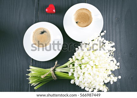 Two cups of coffee - espresso, heart and bouquet of flowers - lilies of the valley on black background. romantic breakfast for my birthday, Valentine's Day.