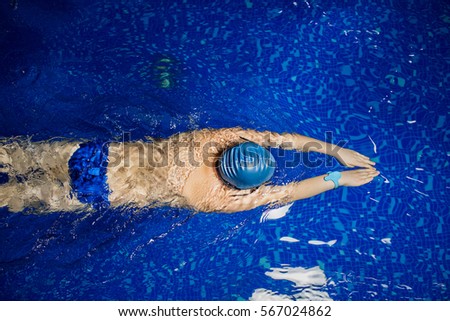 Fit male swimmer swimming with swimming hat in swimming pool, top view Royalty-Free Stock Photo #567024862