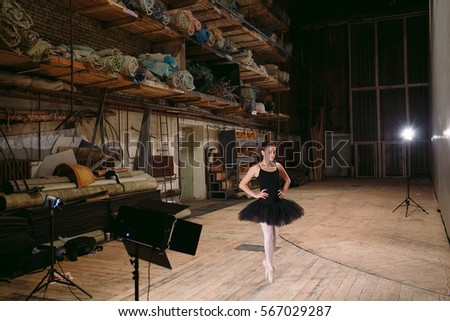 Young ballerina in black dress trains behind the scenes.