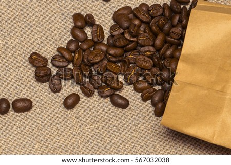 Paper bag with grain coffee on vintage linen background