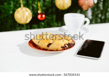 Mobile smartphone, coffee and pastry on light background. Closeup photo flat lay style