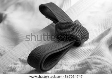 Black martial arts belt tied in a knot with white kimono in background Royalty-Free Stock Photo #567034747