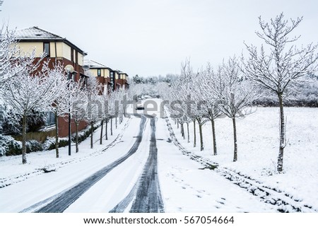Tracks on road to residential area covered by snow in UK winter, Milton Keynes