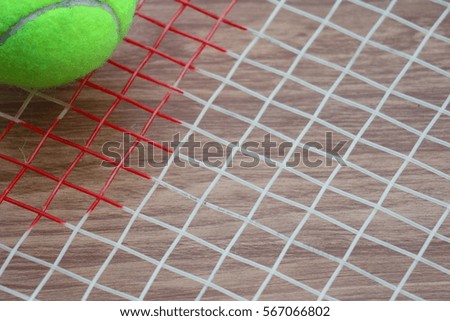Tennis ball on racket net on wood background, sport equipment