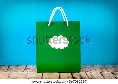 Green Paper Bag with an icon cloud on blue background.