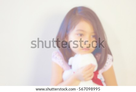 a blurred picture of cute toddler girl feeling sad and hugging her white teddy bear tightly isolated on white background, filtered tones