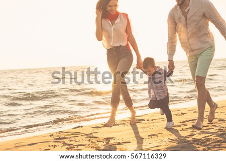 happy young family have fun on beach run and jump at sunset Royalty-Free Stock Photo #567116329