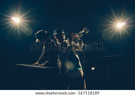 Musician Duo band playing a Trumpet and keyboard on black background with spot light and lens flare, musical concept